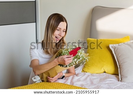 Beautiful young caucasian woman holding bouquet of flowers in bedroom. Happy Valentines day. distant relationship and love concept