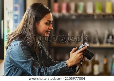 beautiful female photographer holding camera taking photograph indoors