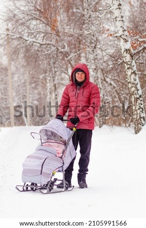 a man walks with a child on a sled in winter