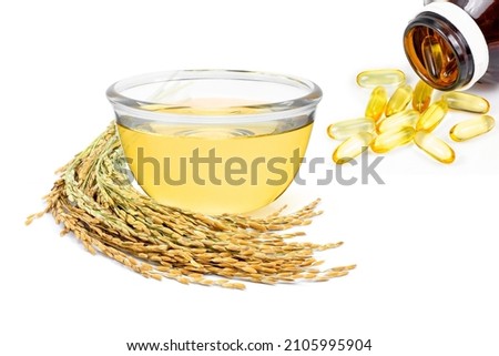 Rice bran oil extract and soft gel capsule with paddy unmilled rice on white background. Royalty-Free Stock Photo #2105995904