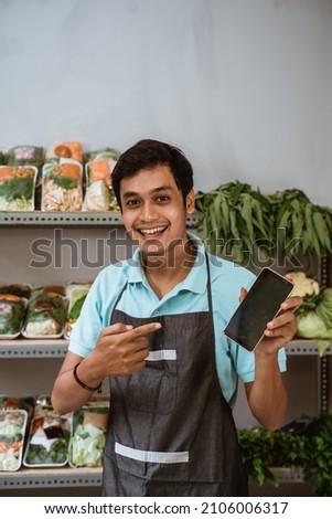 Salesman holding a mobile phone with finger pointing Royalty-Free Stock Photo #2106006317