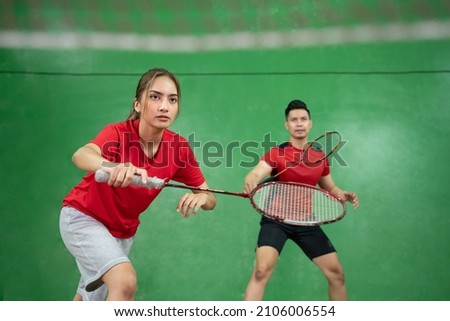 Beautiful badminton player in a stance with her male partner Royalty-Free Stock Photo #2106006554