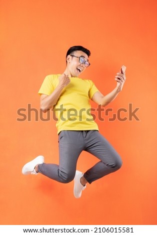 Asian man in yellow t-shirt jumping on orange background	 Royalty-Free Stock Photo #2106015581