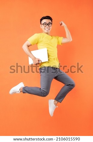 Asian man in yellow t-shirt jumping on orange background	