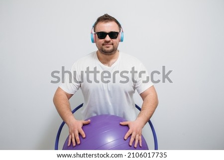 Funny image of a fat guy holding a hula hoop and exercise ball isolated white background. Fitness time. Time to lose weight concept.