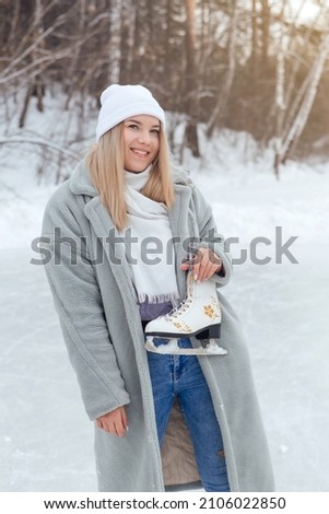 Lovely young woman with ice skates on the ice rink. Girl is going to skating on ice in a winter frosty day