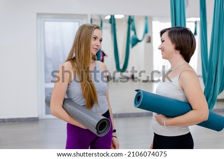 Two happy women friends holding yoga mat and ready to start workout together yoga or pilates exercise indoor