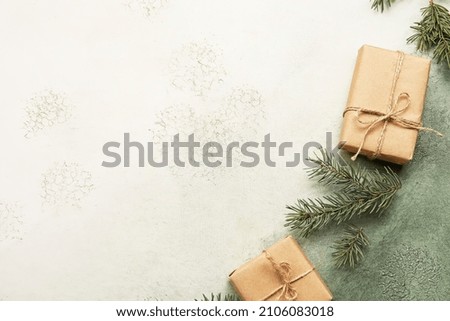Fir tree branches and gift boxes on white and green background