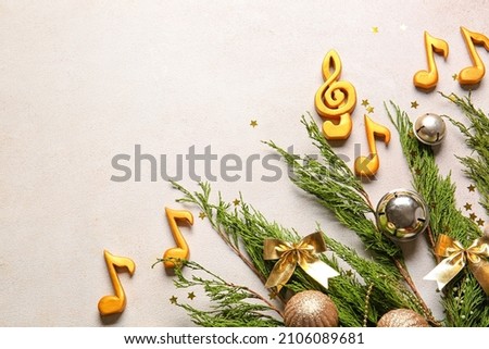Fir tree branches with Christmas decor, note signs and treble clef on light background