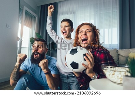 Family of fans watching a football match on TV at home Royalty-Free Stock Photo #2106092696