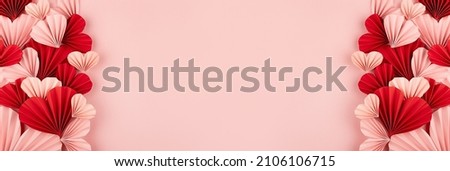 Fun Valentines day festive banner in asian style - many pink and red paper hearts of folded fans on gentle pastel pink color backdrop as sideways border with copy space, frame, top view.