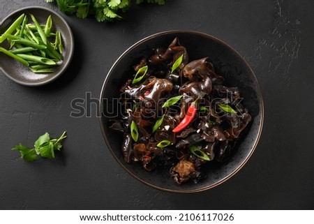 Chinese tree ear black muer mushrooms with chilli pepper on black background. Top view. Pan-Asian food. Royalty-Free Stock Photo #2106117026