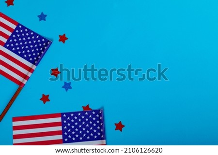 Overhead view of small america flags on sticks by glitter stars by copy space over blue background. patriotism, symbol and identity.