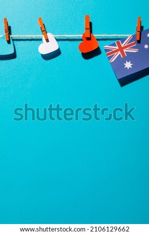 Australia flag and heart shapes hanging on clothesline with copy space over blue background. patriotism, symbol and identity.
