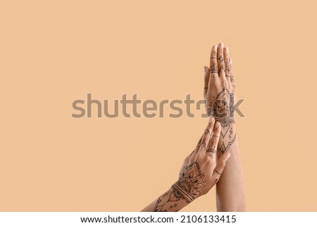 Female hands with henna tattoo on color background
