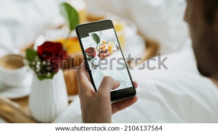 Valentines Day Concept. Handsome Ethnic Man Taking a Photo of a Beautiful Looking Breakfast Tray With Croissants and Coffee. Celebrating the Valentines Day With His Girlfriend in a Fancy Hotel.