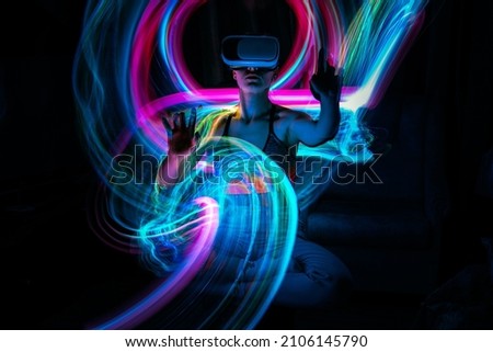 Metaverse digital Avatar, Metaverse Presence, digital technology, cyber world, virtual reality, futuristic lifestyle. Woman in VR glasses playing AR augmented reality NFT game with neon blur lines Royalty-Free Stock Photo #2106145790