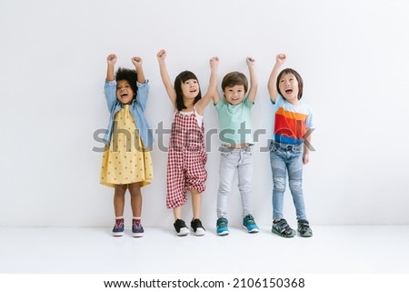 Group of Diverse Ethnicity Little kids raising hands up and smiling Isolated on gray background. Childhood, freedom, happiness, active lifestyle concept. Royalty-Free Stock Photo #2106150368