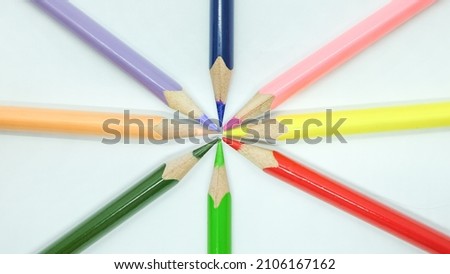 Different color pencils converge on white background. Isolated close up shot. 