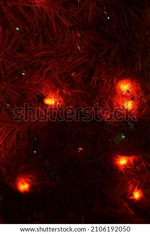 Glowing lights for Xmas Holiday greeting card design decoration. Christmas background in red colors. New Year theme. Lights of a red garland on a Christmas tree.