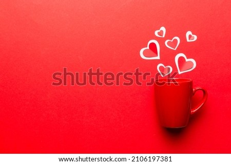 red cup on colored background, splashes of red little hearts, top view with copy space.