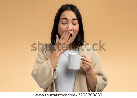 Woman holding cup of tea or coffee in hand at morning, sleepy and tired, wants to sleep, while yawning. Night Owl type concept  Royalty-Free Stock Photo #2106200630