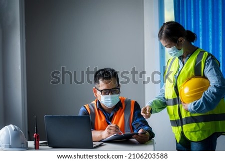 Engineer and architect protects himself from covid-19 (coronavirus) with a protective mask working with laptop computer in the construction site.