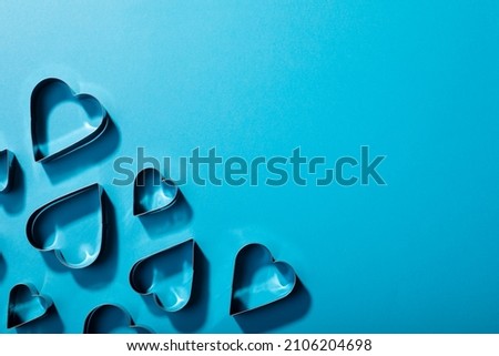 Overhead view of heart shaped cookie cutters arranged over blue background with copy space. valentine's day and love concept.