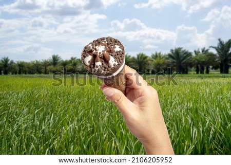 Ice Cream cone in the hand with blurred background of green field