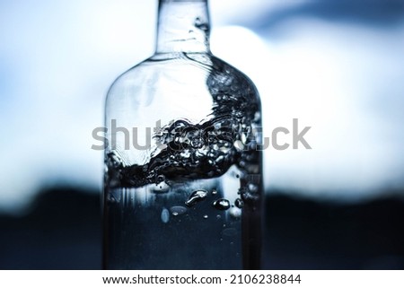 A splash of water in a bottle close-up on a dark, light background. Water details. Water structure