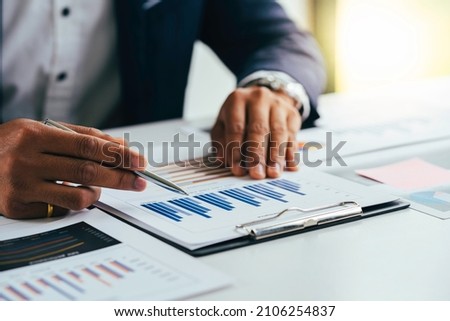 Asian male finance staff Is explaining the performance from the company's rapidly growing bar graph this year. To his boss On the desk at the office, Finance concept