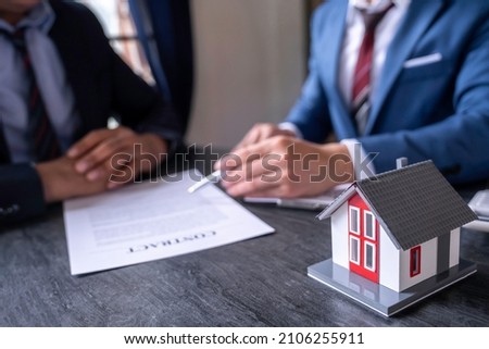 The real estate broker pointed to the insurance contract and was explaining to clients at the exchange office the home insurance idea. home and land mortgage