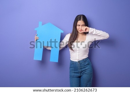 Portrait of beautiful woman  is holding blue  home on purple background 