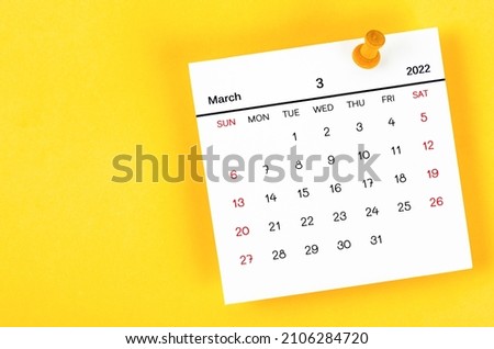 The March 2022 and wooden push pin on yellow background.