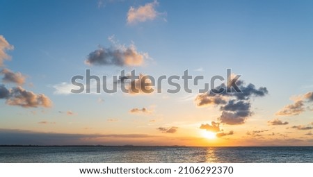 Sunset sky clouds over sea in the evening with orange sunlight golden hour, dusk sky 