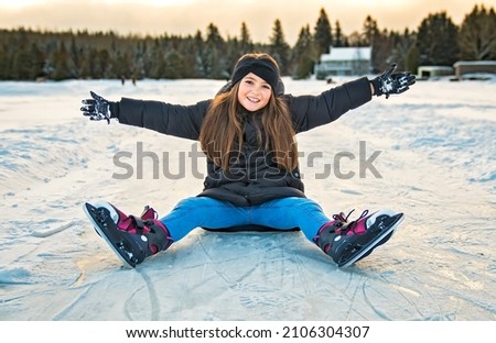 A pretty cheerful little girl in thermal suits skating outdoors