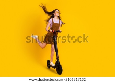 Full length body size view of attractive cheerful dreamy girl riding scooter air blowing isolated over bright yellow color background Royalty-Free Stock Photo #2106317132