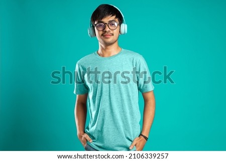 young man using headphones and smiling isolated over blue background