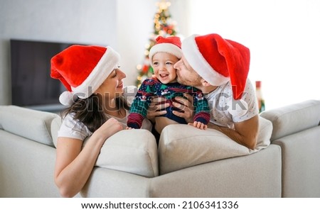 A happy family sitting on sofa with their baby girl on christmas time