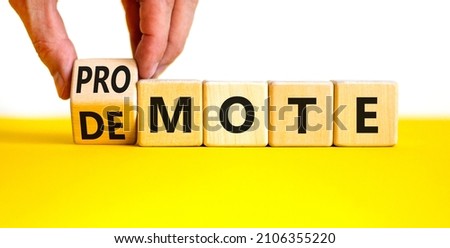 Promote or demote symbol. Businessman turns a cube and changes the word 'demote' to 'promote'. Beautiful yellow table, white background. Business, demote or promote concept. Copy space.