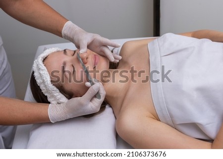 young woman lying on a stretcher in an aesthetic center performing beauty treatment and facial aesthetics with dermapen and dermaplaning techniques Royalty-Free Stock Photo #2106373676