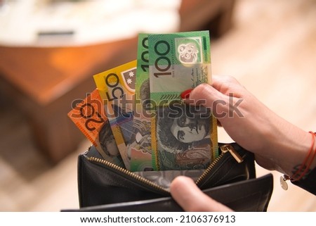 a woman puts Australian dollars in her wallet. A woman is holding an Australian currency. A concept showing the Australian economy Royalty-Free Stock Photo #2106376913
