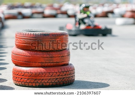a tire on the track at the corner, go-kart and painted tires mark the track boundaries. car entertainment Royalty-Free Stock Photo #2106397607