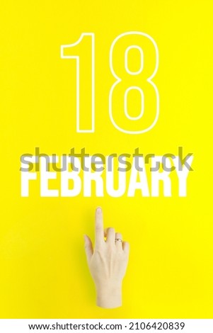 February 18th. Day 18 of month, Calendar date.Hand finger pointing at a calendar date on yellow background.Winter month, day of the year concept
