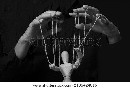 Hands manipulating puppet. Master of marionette in action. Royalty-Free Stock Photo #2106424016