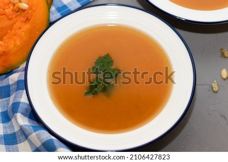 two plates of pumpkin soup on a concrete background and a napkin in a checkered blue