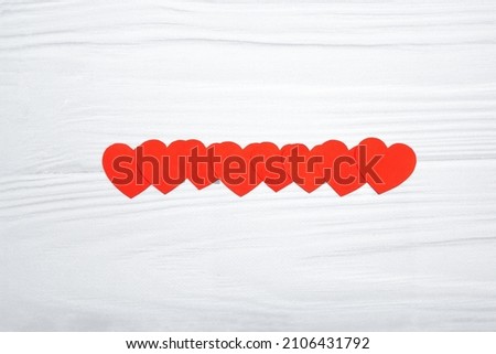 Red paper hearts hanging on white wooden background. Valentinas day