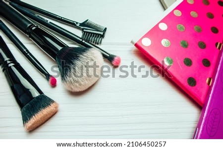 Golden and pink notebooks and makeup brushes on a white wooden background in spring. Spring photography