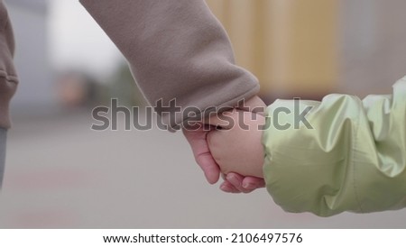 tender hand of mother holds baby hand on walk in park, happy family, mom helps child to go, mommy takes care of kid, touch together, unity of parent person and little son, safe emotion of motherhood Royalty-Free Stock Photo #2106497576