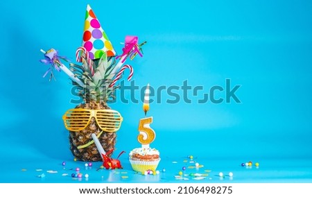 Creative congratulations on five years for a child. Pineapple with glasses in festive decorations. copy space. 5th birthday. Merry fruit birthday card. Royalty-Free Stock Photo #2106498275